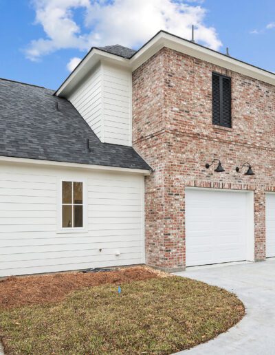 New two-story brick and siding house with double garage doors and a side entrance.