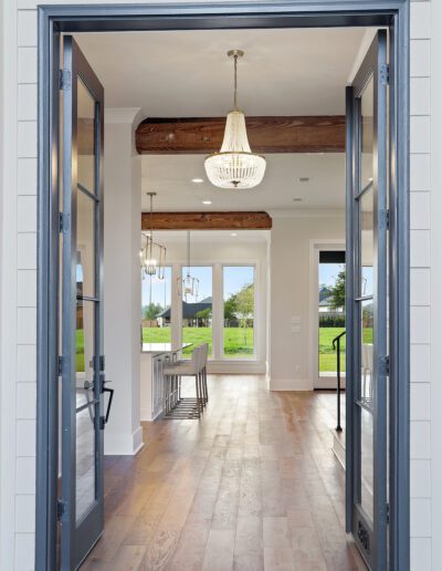Open doorway leading to an elegant interior with hardwood floors and a chandelier.