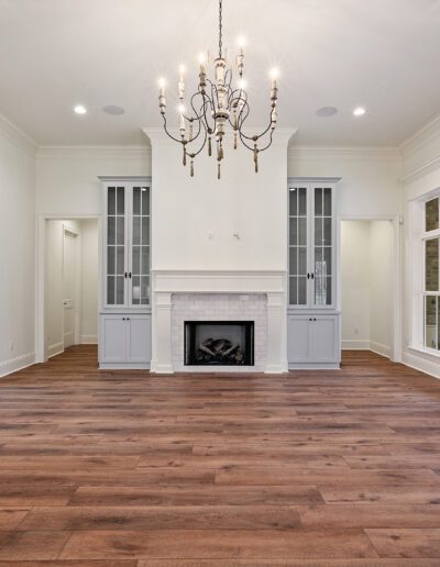 Spacious living room with hardwood floors, white walls, a fireplace, and large windows.