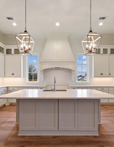 Spacious kitchen interior with white cabinetry, central island, and pendant lighting.