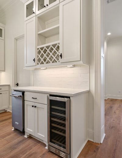 Modern kitchen interior with white cabinetry and a built-in wine cooler.