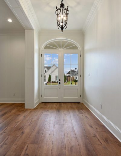 Bright, empty hallway featuring hardwood floors and an arched doorway with a view to the outdoors.