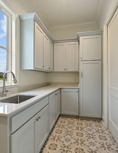 Bright, compact kitchen corner with white cabinetry and patterned flooring.