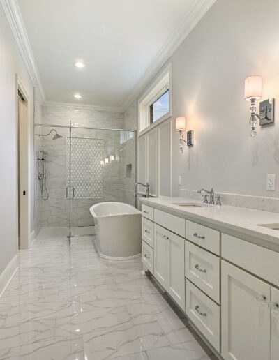 Modern bathroom with double vanity, herringbone tile shower, and freestanding bathtub.
