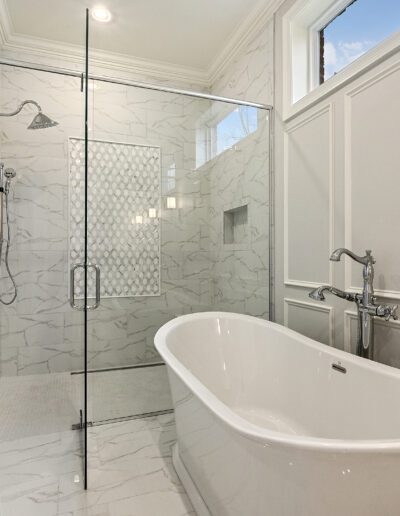 Elegant bathroom with a white freestanding bathtub and a walk-in shower featuring marble walls.