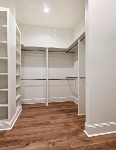 An empty walk-in closet with built-in shelves and hanging rods.