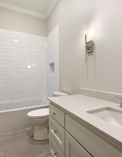 Modern bathroom with a white tiled shower, a single vanity, and tiled flooring.