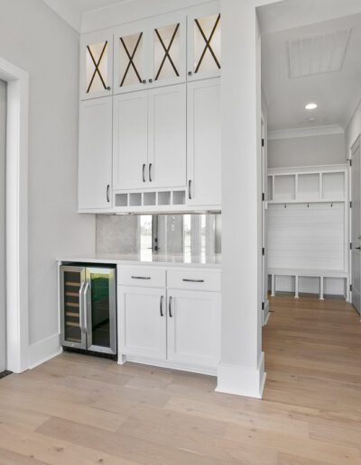 Modern kitchen with white cabinetry, built-in wine fridge, and hardwood floors.