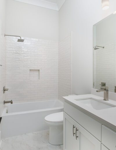 Modern white bathroom with a shower-tub combo, single sink vanity, and a toilet.
