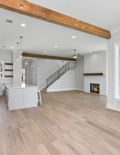 Modern kitchen with stainless steel appliances, white cabinetry, and a fireplace, leading to a staircase with metal balusters.