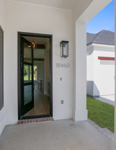 Front porch area of a modern house with the door open, showing an entrance hallway.