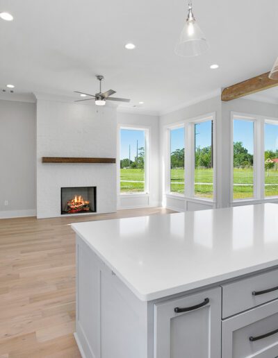 Modern kitchen with a central island, exposed wooden beams, and a view of the outdoors.