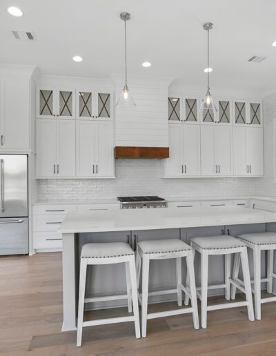 Modern kitchen interior with white cabinetry, stainless steel appliances, and a center island with bar stools.