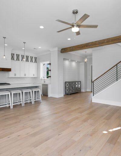 Modern kitchen interior with stainless steel appliances, white cabinetry, and a wooden staircase.