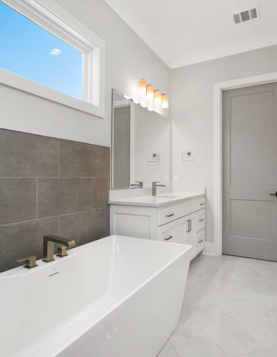 Modern bathroom with a freestanding bathtub, gray tiles, and white vanity.