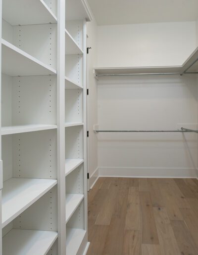 Empty walk-in closet with built-in shelves and hanging rods.