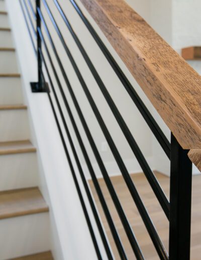 Modern staircase with wooden handrail and black metal balusters.